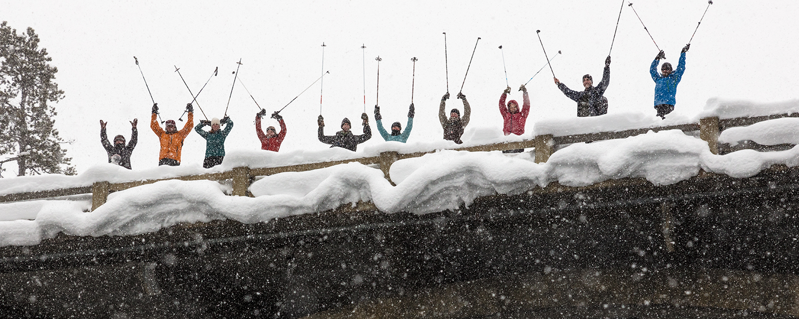 Cross-country skiers raise their ski poles on a bridge