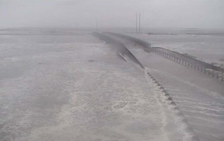 Ocean water washing across low bridge