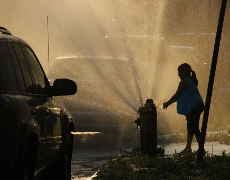 Girl plays in water from fire hydrant